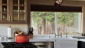 Une cuisine moderne avec un plan de travail en marbre, une casserole rouge et un plafond en bois.