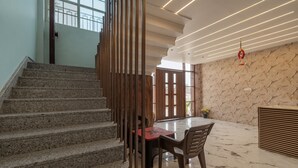 Un intérieur moderne avec un sol en marbre, un escalier et un coin repas comprenant une table et des chaises.