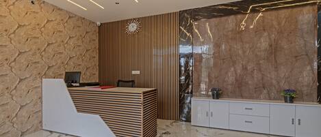 A modern reception area with a wooden reception desk, a clock, and a marble wall.