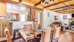 A spacious kitchen with wooden beams, a dining area with a glass table, and a cozy living room with a fireplace.