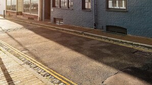 A street view with a row of buildings, including a shop with large windows and a blue building with a brick facade. - Old Post Office - Large house with games room +bar (Ramsgate)