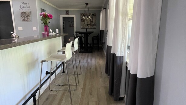 A modern kitchen with a bar area, white bar stools, and a dining table with chairs. - 3-bedroom vacation home just 2 minutes to Lake Michigan (Traverse City)