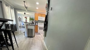 A modern kitchen with wooden flooring, a central island, and a dining area with bar stools. - 3-bedroom vacation home just 2 minutes to Lake Michigan (Traverse City)