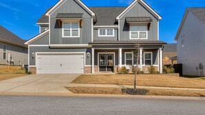 A two-story house with a garage, a front porch, and a small front yard. - Perfect Master's Rental (Grovetown)