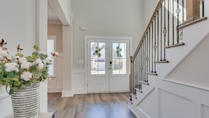 A hallway with a wooden floor, white walls, and a white door with glass panels. - Perfect Master's Rental (Grovetown)
