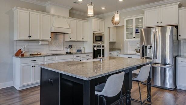 A modern kitchen with white cabinetry, stainless steel appliances, and a granite island. - Perfect Master's Rental (Grovetown)