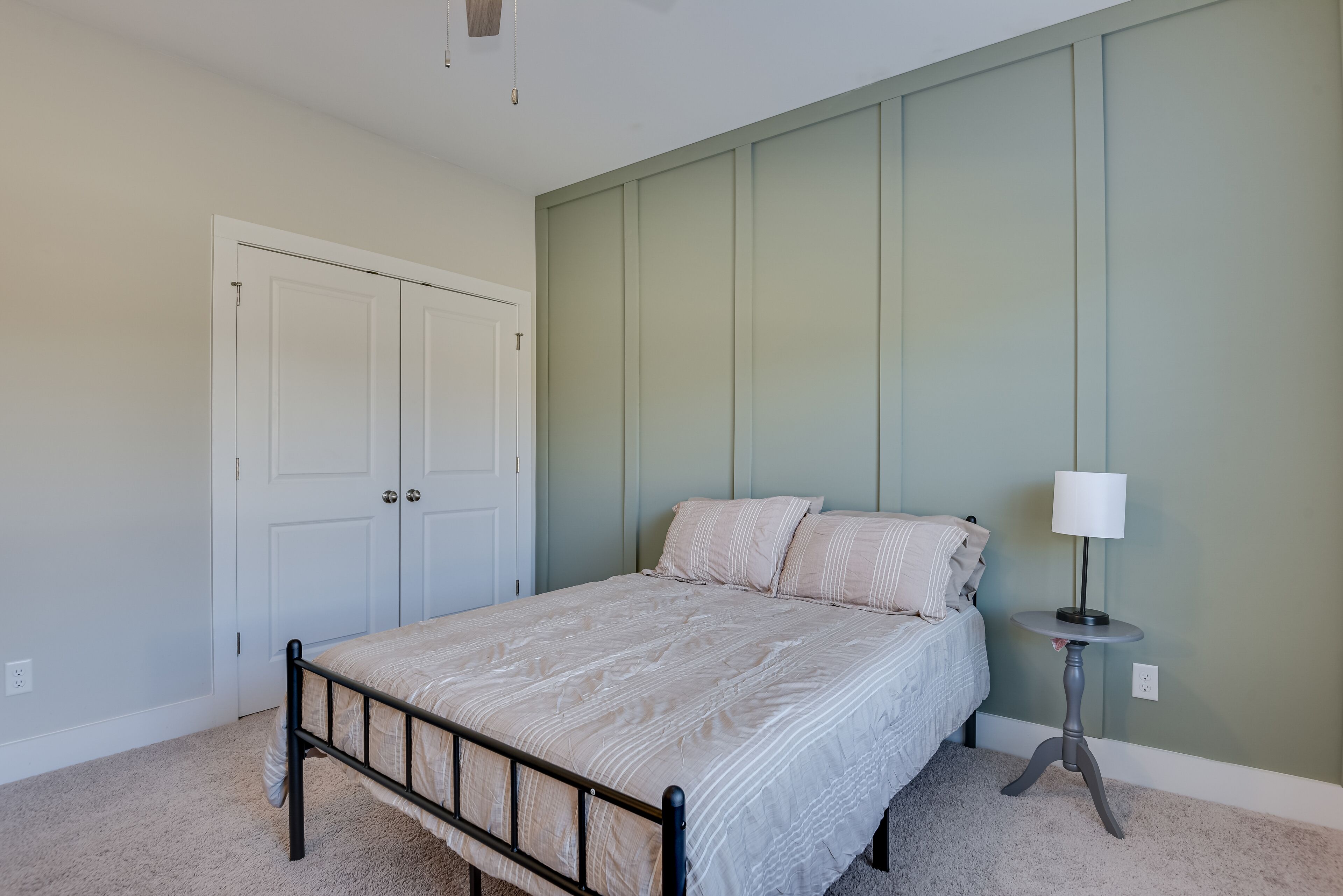 A bedroom with a bed, a nightstand, a lamp, and a wardrobe.