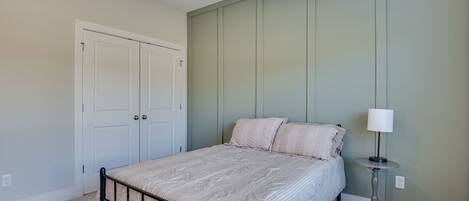 A bedroom with a bed, a nightstand, a lamp, and a wardrobe.