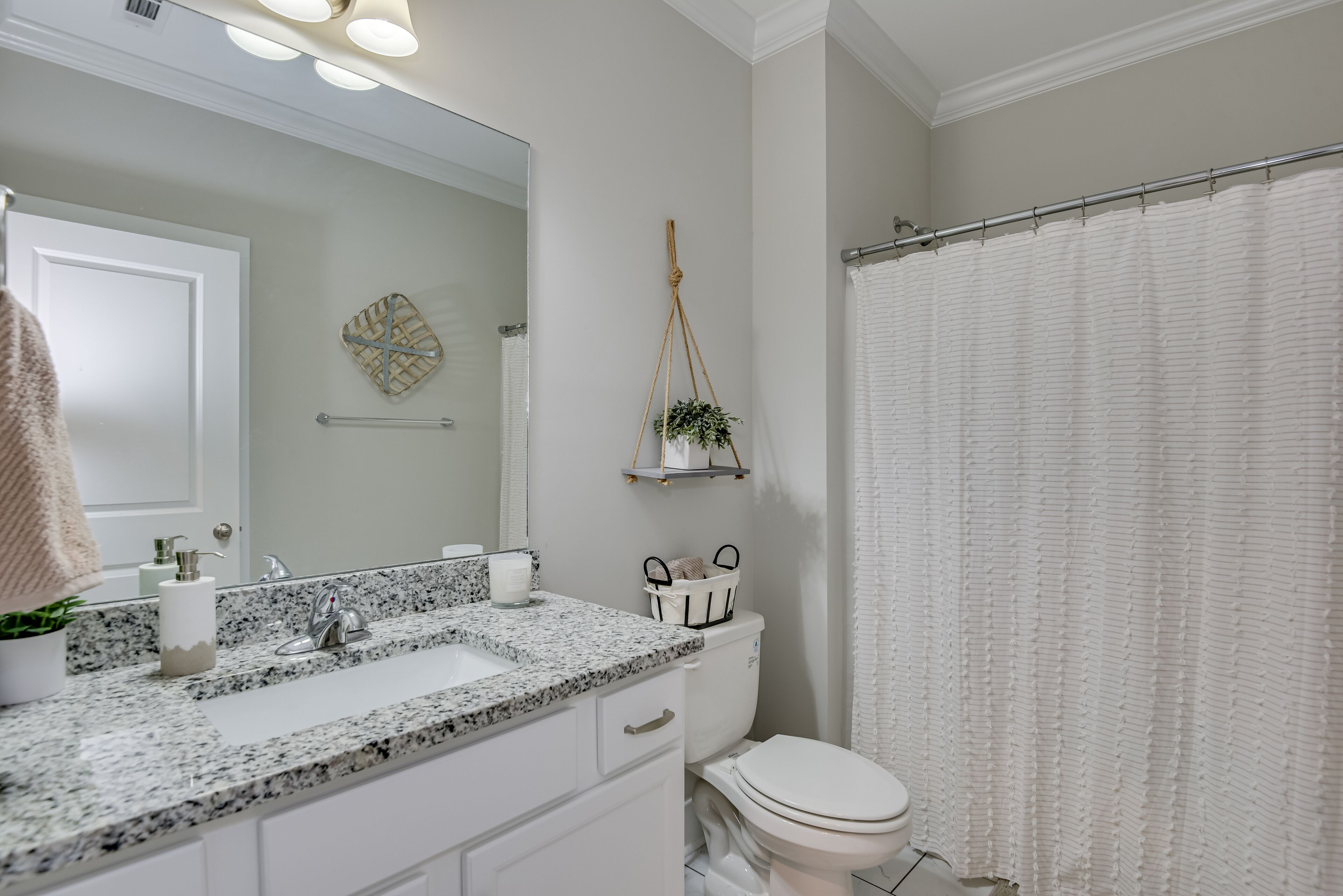 A bathroom with a white sink, a mirror, a toilet, and a shower curtain.