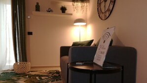 Un salon confortable avec un canapé, une petite table ronde, une lampe et un panneau indiquant que le Wi-Fi est gratuit.