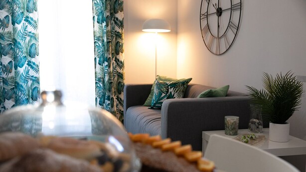 Un salon moderne avec un canapé, une lampe, une horloge et une table sur laquelle se trouvent un gâteau et des objets décoratifs.