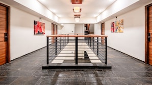 A modern hotel hallway with a central staircase, wooden doors, and artwork on the walls. - Treebo Premium The Memoir, Ramdaspeth (Nagpur)