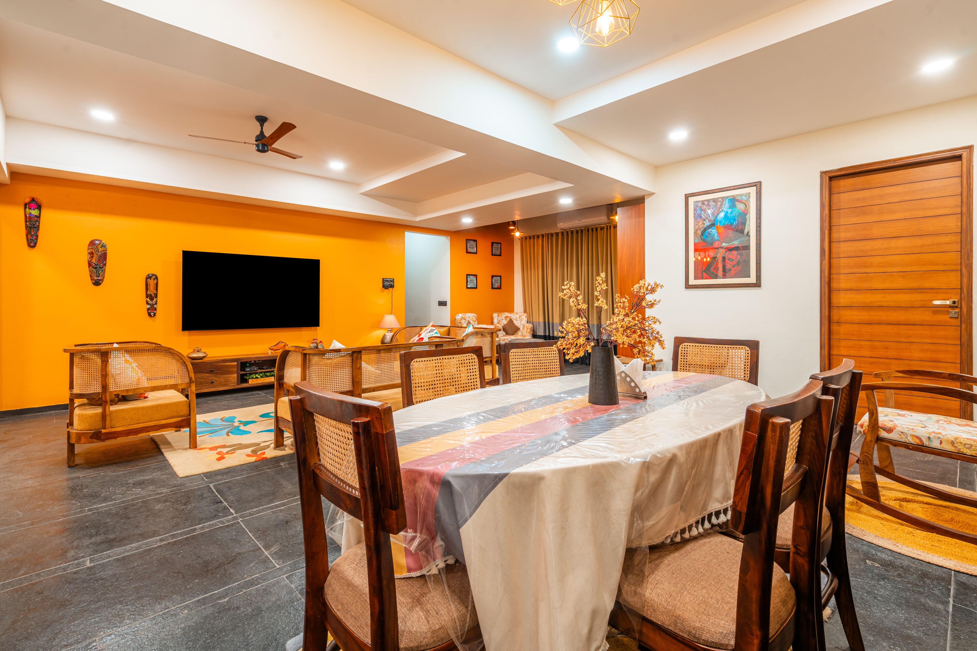 A dining area with a large table, chairs, a ceiling fan, and a television.