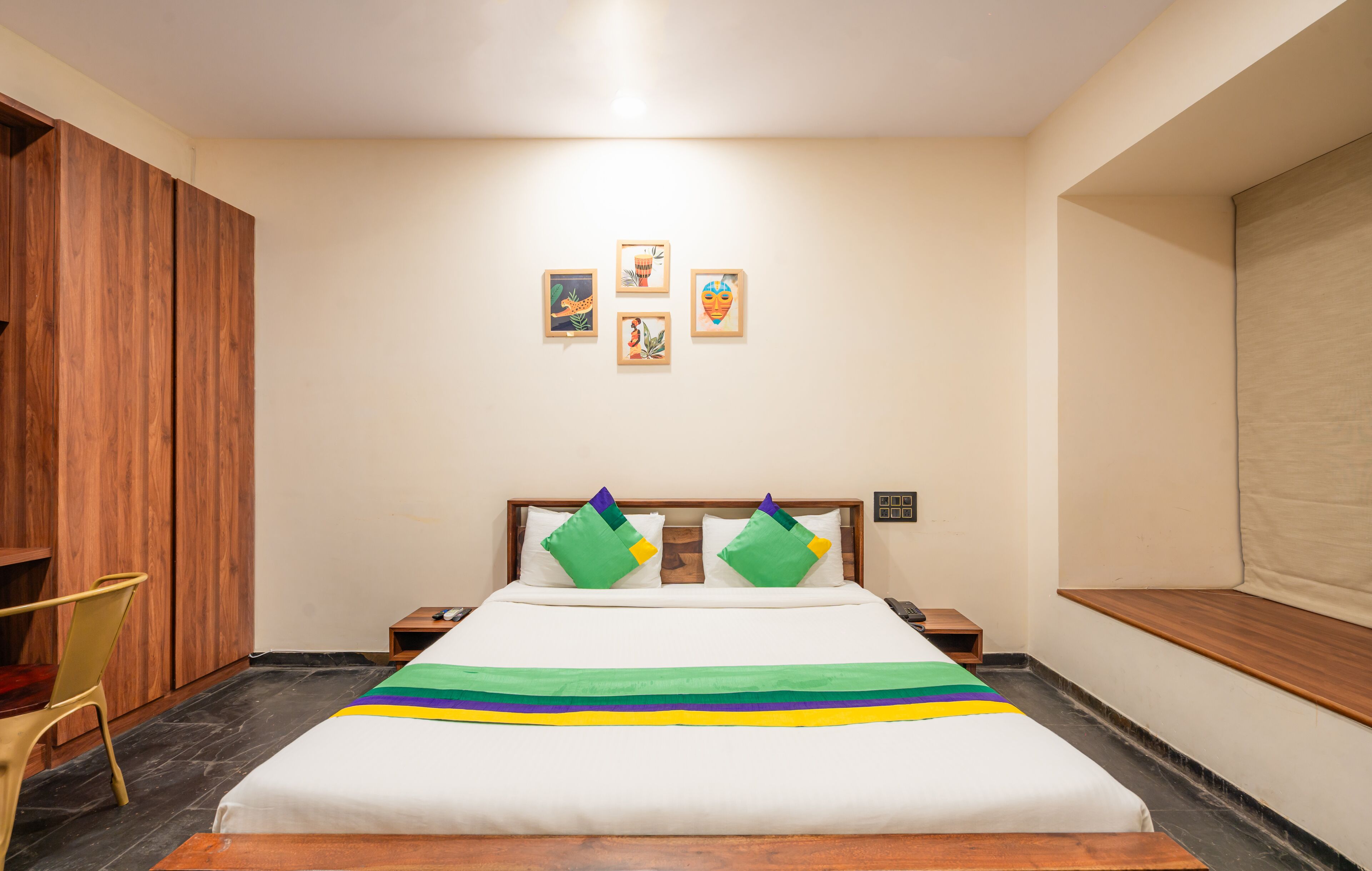 A hotel room with a bed, a wooden wardrobe, a chair, and a nightstand.