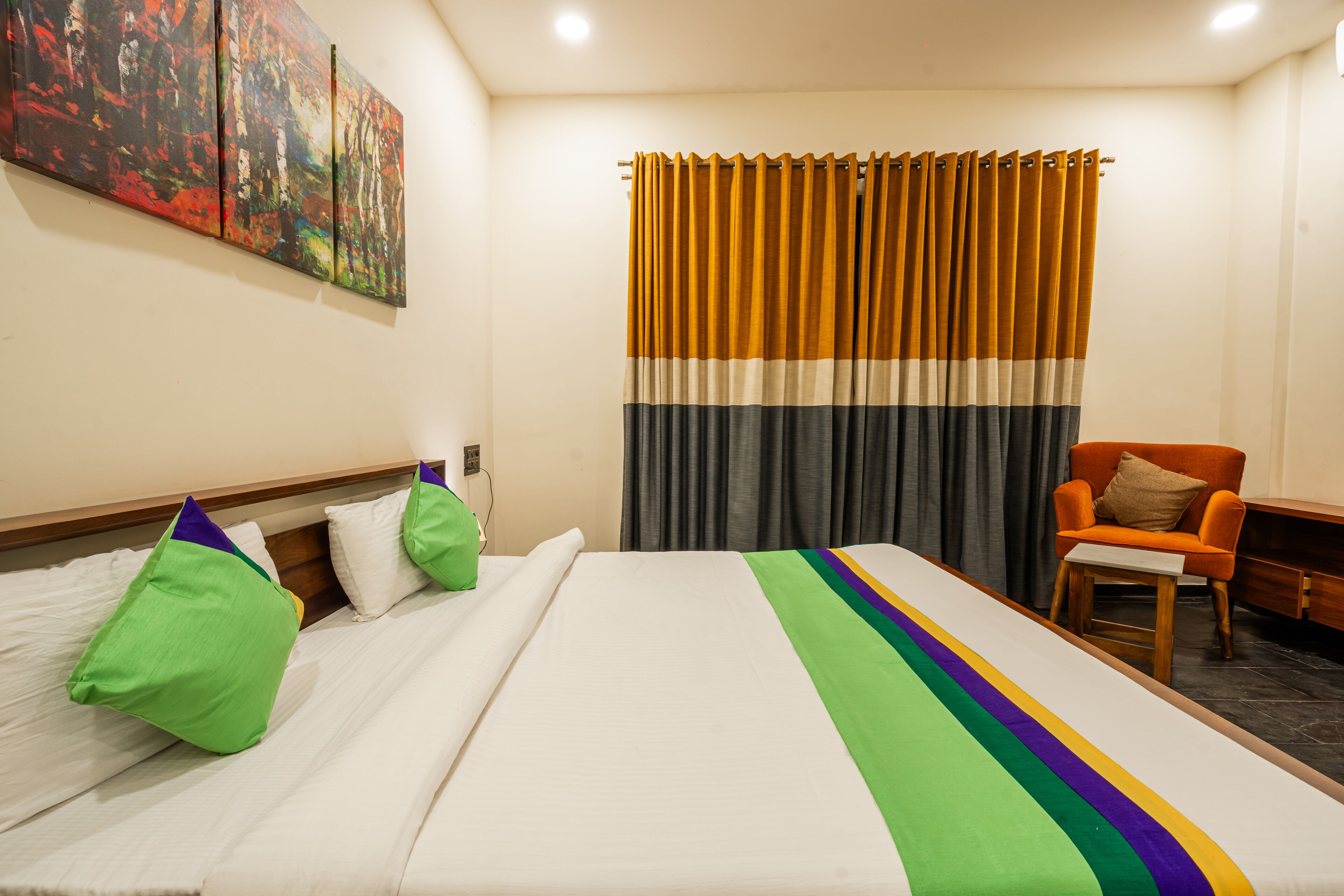 Een hotelkamer met een opgemaakt bed, een stoel en een groot schilderij aan de muur.