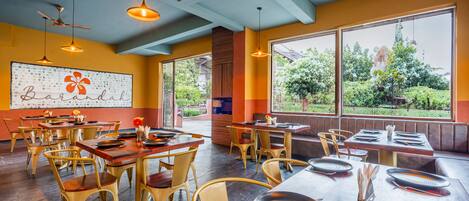 A restaurant with wooden tables and chairs, large windows, and ceiling fans.