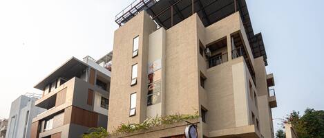 A multi-story building with a flat roof, large windows, and a sign for 'Treebo The Memoir'.