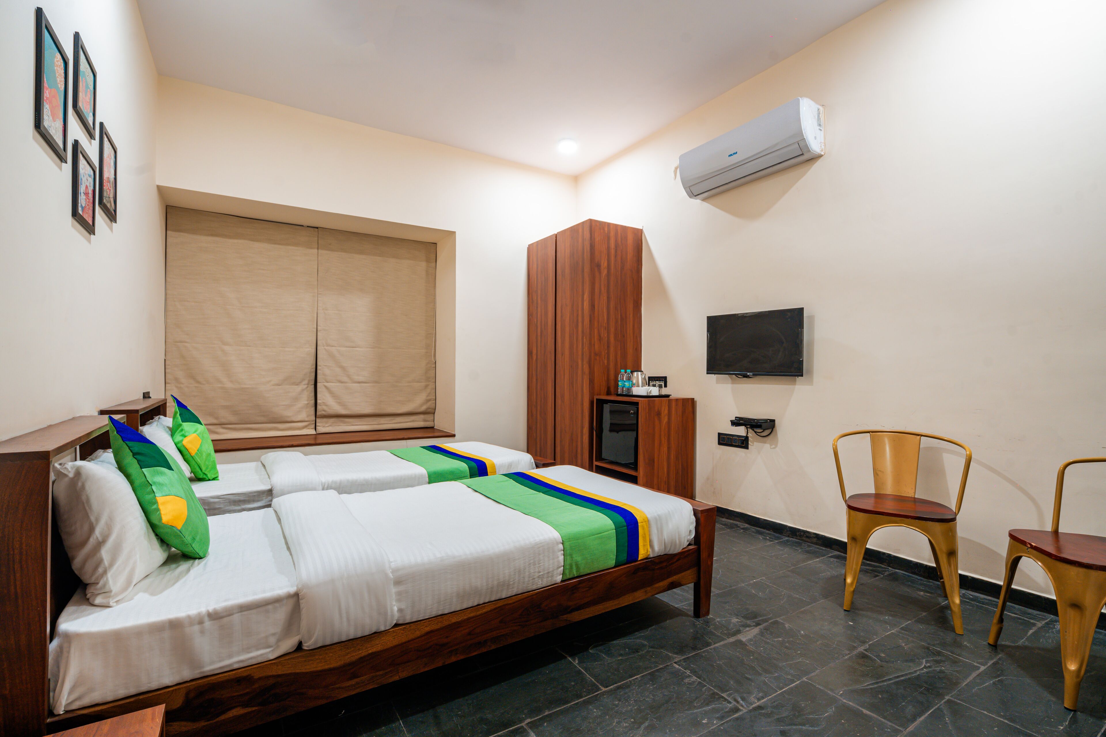 A hotel room with two beds, a TV, a wardrobe, and a desk with a chair.