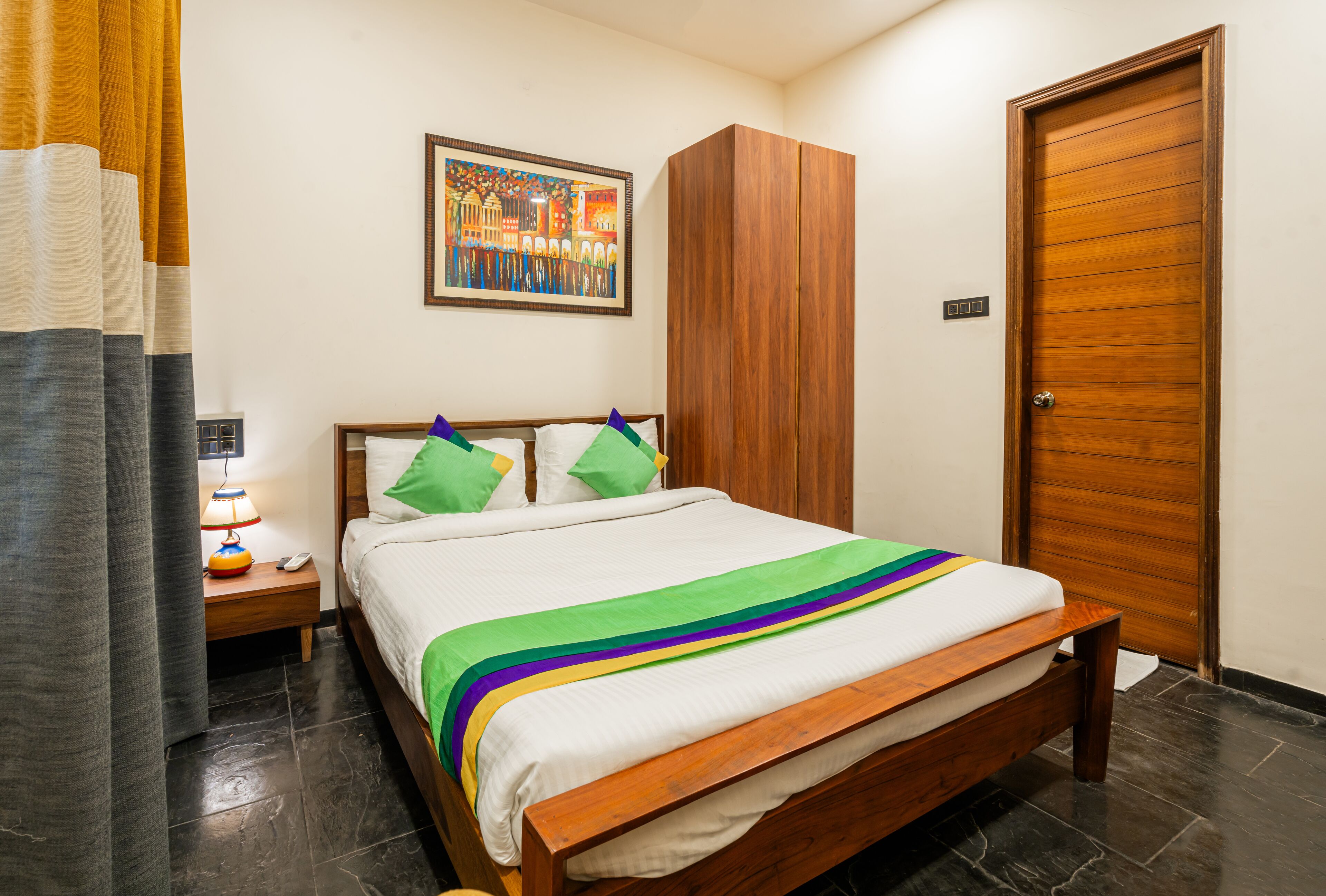 A neatly arranged bedroom with a bed, a nightstand, a wardrobe, and a door.