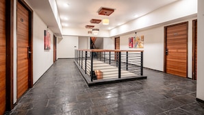 A hallway with wooden doors, a central staircase, and a tiled floor. - Treebo Premium The Memoir, Ramdaspeth (Nagpur)