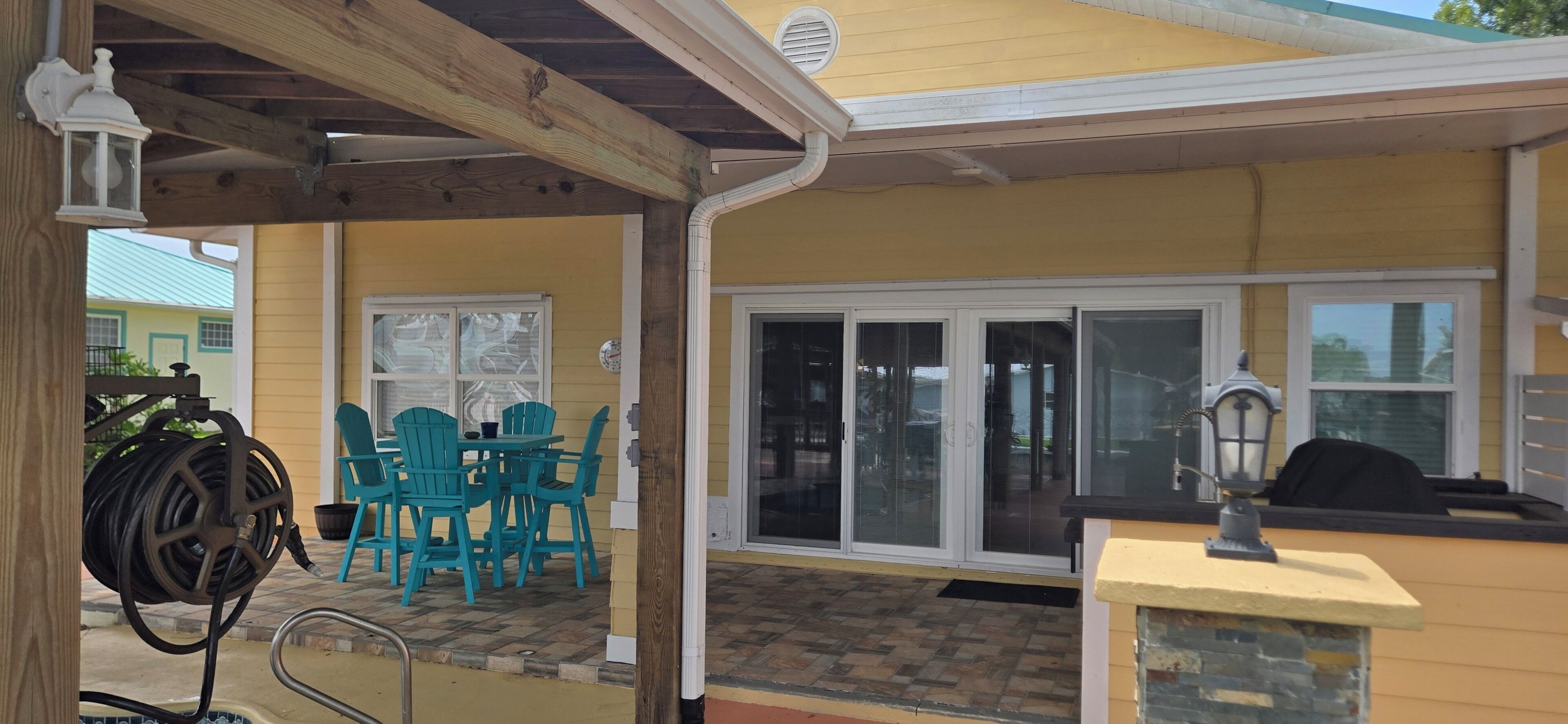 Un patio couvert avec des sièges d’extérieur, une piscine et une porte de garage.
