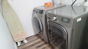 Un área de lavandería con dos lavadoras y una secadora, suelo de madera y un perchero para toallas.