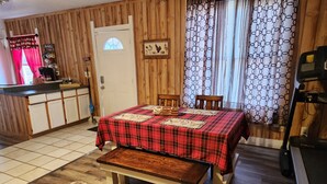 Una habitación acogedora con cama, un banco, una mesa de comedor con sillas, una zona de cocina y un televisor.