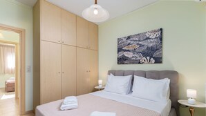 Et pænt indrettet soveværelse med seng, garderobeskab, natbord og vægmonteret lampe.
