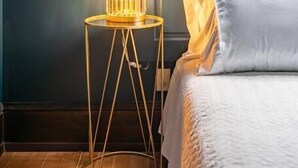 A bedroom with a bed, a bedside table with a lamp, and a window with a view of the sky. - Charming Room in Historic BnB - Rm6 (Seattle)