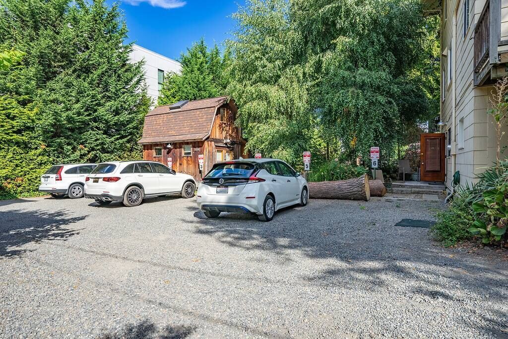 A gravel driveway leading to a wooden cabin with two parked cars.