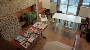 A spacious room with a brick fireplace, a long table with magazines, and several chairs. - Parking, tv, ski locker, 95m², Les Angles (Les Angles)