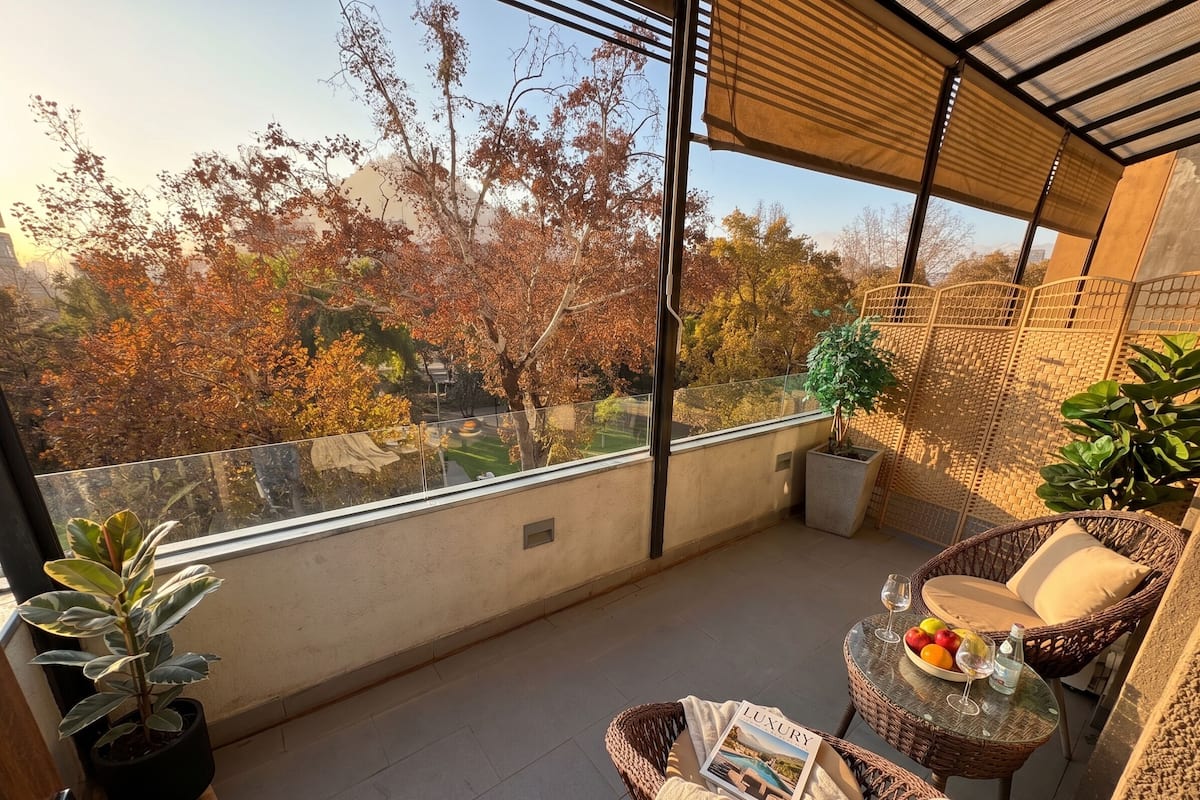 A balcony with a wicker chair, a small table with a magazine, and potted plants.