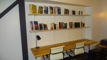 Un espacio de trabajo con un escritorio de madera, dos sillas de oficina blancas y una estantería con varios libros.