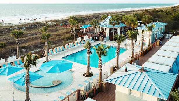 Ein Resort mit mehreren Schwimmbecken, Liegebereichen und Blick auf den Strand.