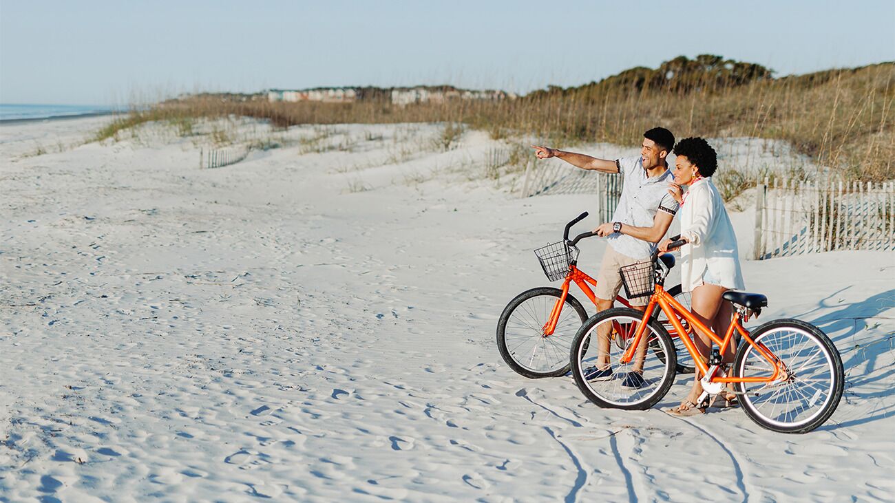 A sandy beach with a bicycle and two people.