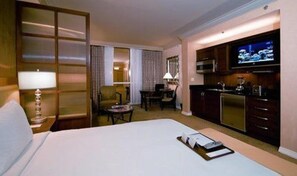 Relax in this cozy space with a large bed, a sitting area, and a kitchenette featuring a microwave, toaster, and TV.