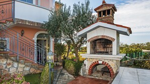 Una escalera de piedra que conduce a una puerta, un horno de ladrillo y un jardín con un árbol y arbustos.