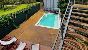 A rooftop pool area with a view of the city, a wooden deck, and a staircase leading to a covered upper level. - Pupa House  (Tamarindo)