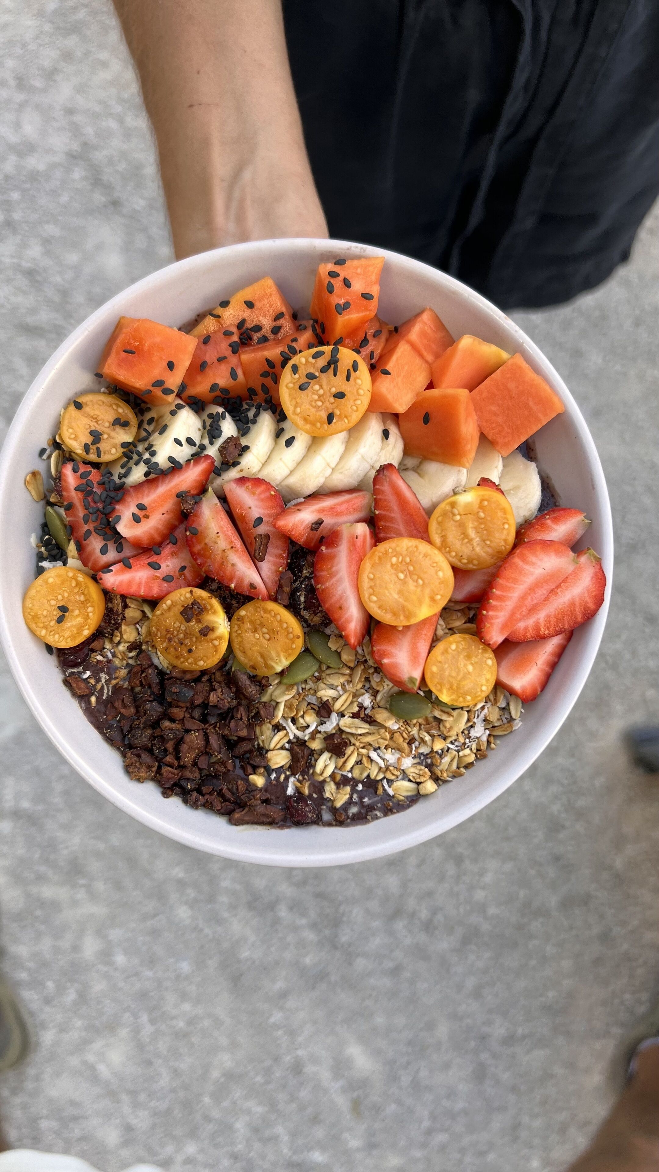 A bowl of mixed fruits and granola.