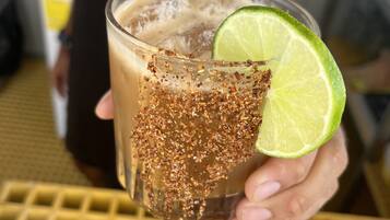 A person holding a glass with a lime slice and a beverage garnished with spices.