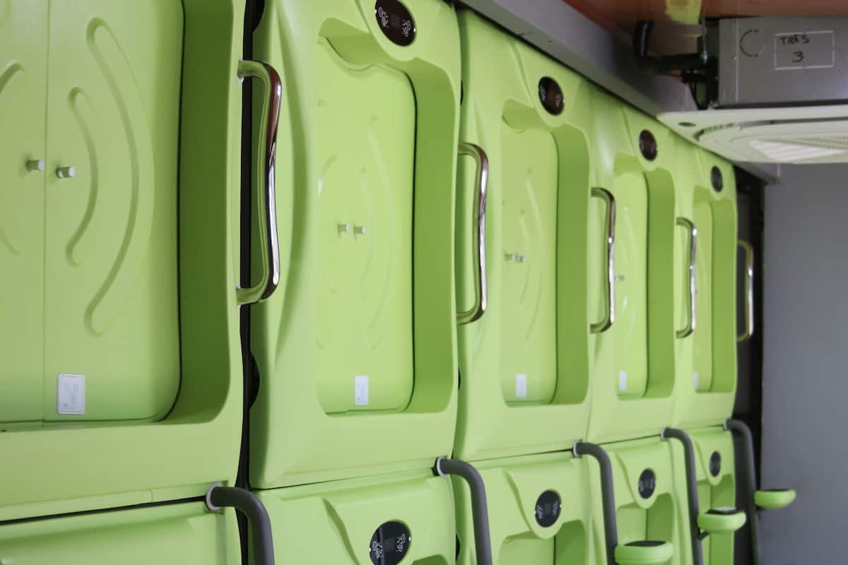 A row of green lockers with handles and a control panel above.