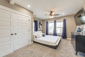 Ein Schlafzimmer mit Bett, Deckenventilator, Kommode und Fernseher.