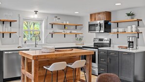 A modern kitchen with wooden bar stools, a built-in island, and stainless steel appliances. - Hot Tub*Borders National Park*Near Massanutten Resort*42 Acres*Private (Elkton)
