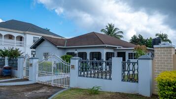 A two-story house with a gated entrance, a balcony, and a number '33' sign.