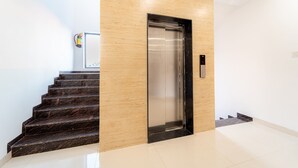 Un ascensor moderno con detalles metálicos, un revestimiento de madera y una escalera de mármol.