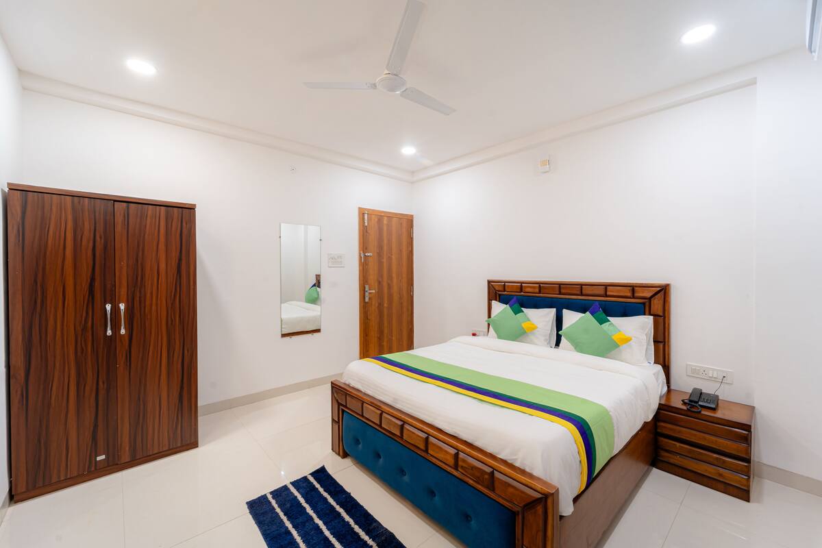 A bedroom with a wooden bed, a wardrobe, a mirror, and a ceiling fan.