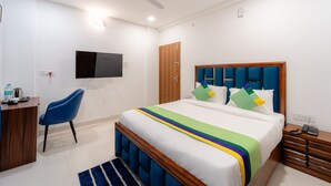 Una habitación de hotel con una cama, un escritorio, una silla, un televisor, un ventilador de techo y una puerta de madera.