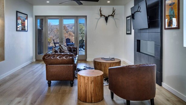 A spacious living room with a large window, a ceiling fan, a mounted deer head, and a fireplace. - Peaceful creek-country escape that feels almost magical, with a private trail to Oak Creek and a cedar hot tub off the master bath. Very private, yet 10 min to wineries and 25 min to Sedona. Usually 10-15 degrees cooler than Phoenix. (Cornville)