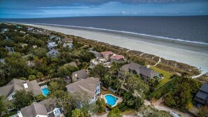 Luchtbeeld van een kustgebied met woonhuizen, een strand en een zwembad.