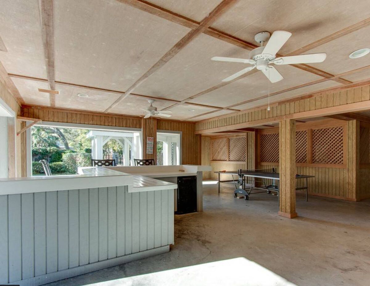 Ruime binnenruimte met een hoge plafond, houten lambrisering, een centraal eiland met spoelbak en een plafondventilator.